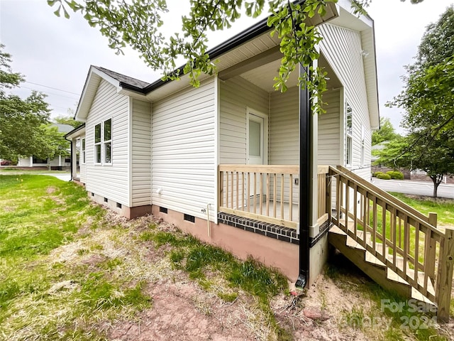 view of property exterior with covered porch and a lawn