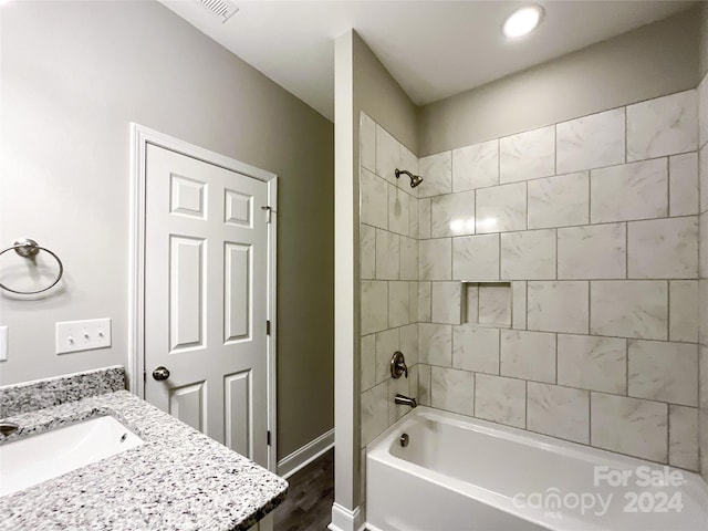 bathroom featuring wood-type flooring, vanity, and tiled shower / bath combo