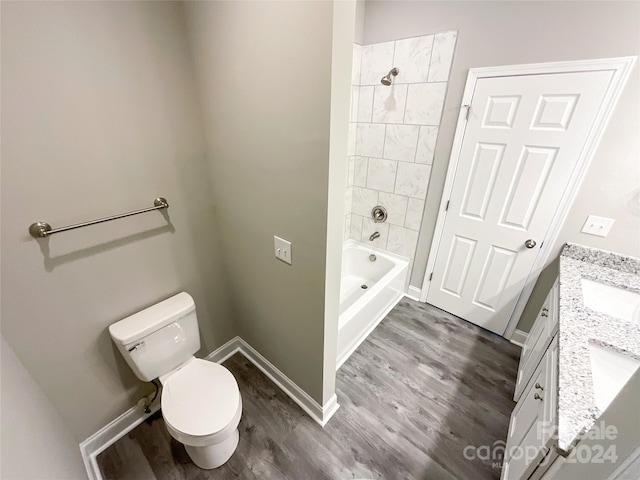 full bathroom with tiled shower / bath, vanity, hardwood / wood-style flooring, and toilet