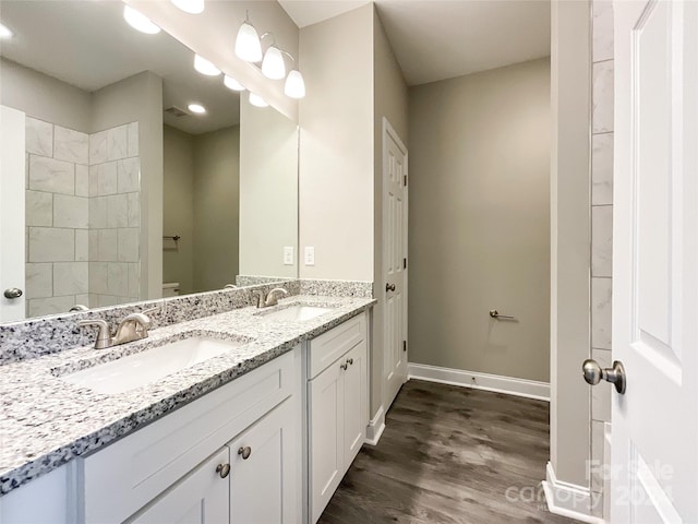 bathroom featuring wood-type flooring, vanity with extensive cabinet space, and dual sinks