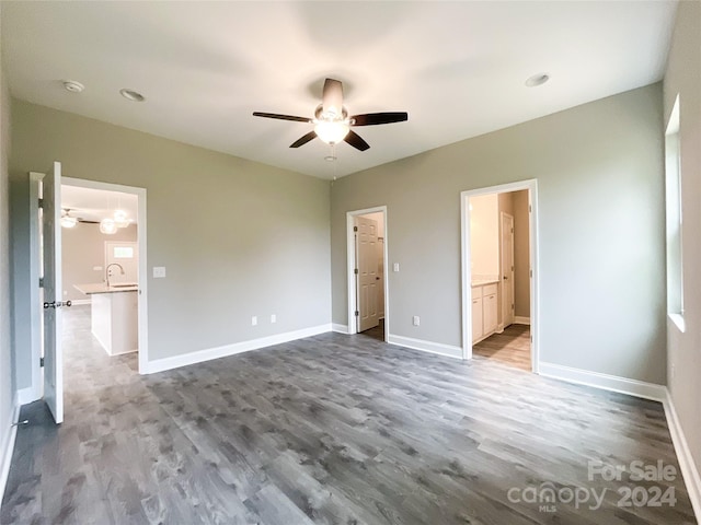 unfurnished bedroom with wood-type flooring, ceiling fan, ensuite bath, and sink