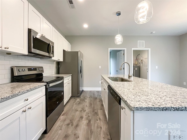 kitchen featuring decorative light fixtures, light hardwood / wood-style flooring, backsplash, stainless steel appliances, and sink