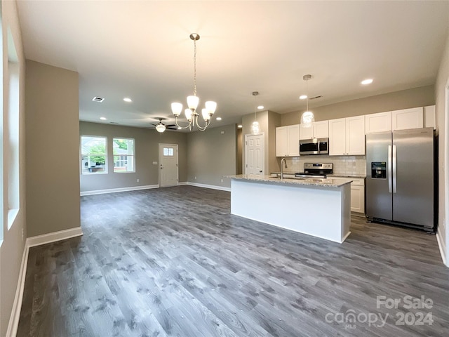 kitchen featuring appliances with stainless steel finishes, white cabinets, backsplash, wood-type flooring, and pendant lighting