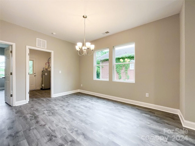 spare room with dark hardwood / wood-style floors, electric water heater, and a chandelier