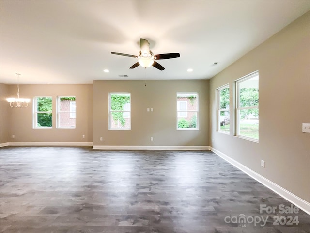 spare room with ceiling fan with notable chandelier and a wealth of natural light