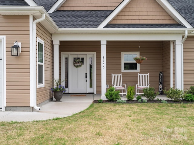 doorway to property with covered porch and a yard