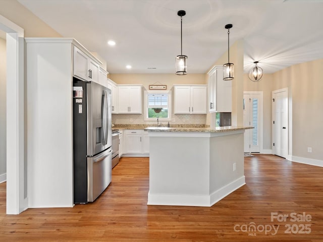 kitchen with backsplash, stainless steel appliances, light stone counters, white cabinets, and light wood-type flooring