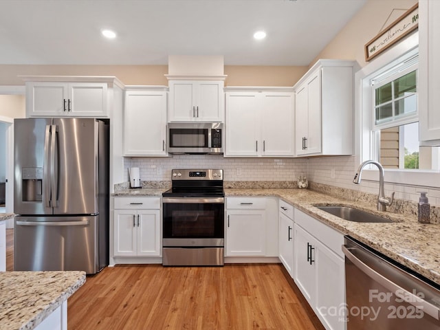 kitchen featuring sink, light hardwood / wood-style flooring, white cabinets, stainless steel appliances, and backsplash