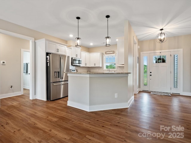 kitchen with pendant lighting, white cabinetry, kitchen peninsula, stainless steel appliances, and light stone countertops