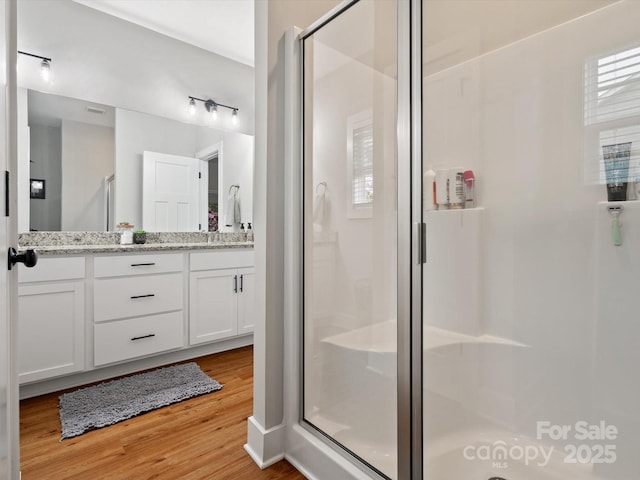 bathroom with vanity, hardwood / wood-style flooring, and a shower with door