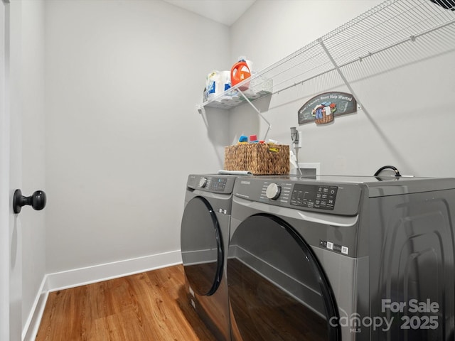 clothes washing area with hardwood / wood-style flooring and independent washer and dryer