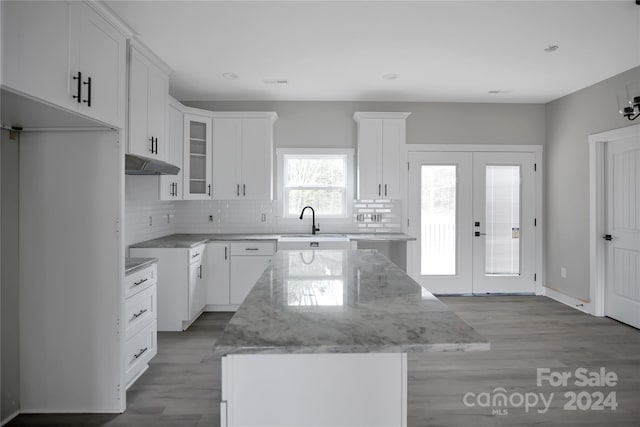 kitchen with white cabinetry, light stone countertops, a center island, and sink