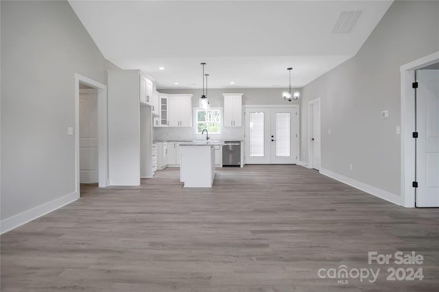 kitchen featuring sink, decorative light fixtures, light wood-type flooring, a kitchen island, and white cabinets