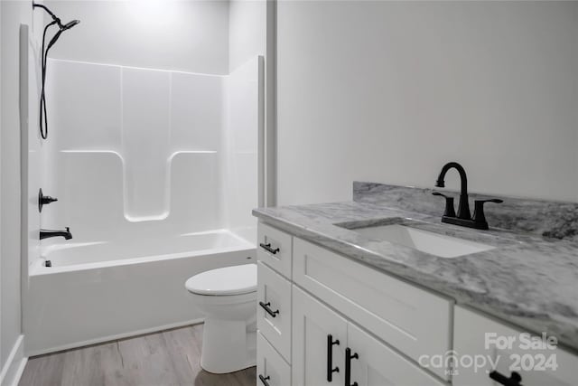 full bathroom featuring vanity, hardwood / wood-style flooring, toilet, and washtub / shower combination