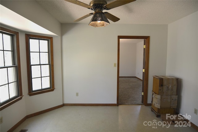 unfurnished room with ceiling fan and a textured ceiling