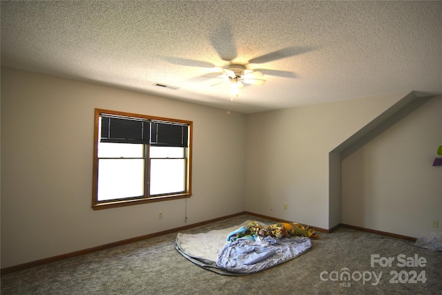 empty room with a textured ceiling, ceiling fan, and carpet