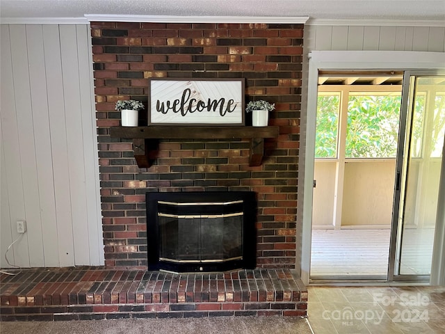 interior details with ornamental molding, dark tile floors, a brick fireplace, and a textured ceiling