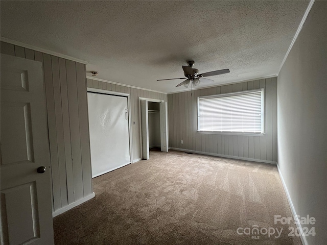 unfurnished room featuring ceiling fan, dark carpet, crown molding, and a textured ceiling