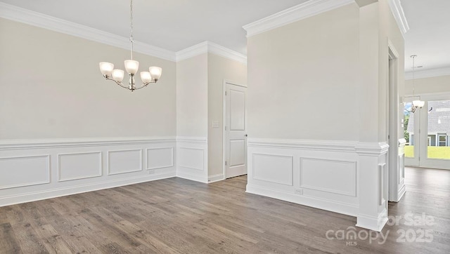 unfurnished dining area featuring crown molding, dark hardwood / wood-style floors, and a chandelier