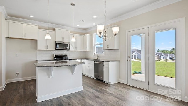 kitchen featuring white cabinets, appliances with stainless steel finishes, a center island, and dark stone countertops