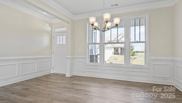 unfurnished dining area featuring ornamental molding, hardwood / wood-style floors, and a chandelier