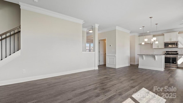 unfurnished living room with an inviting chandelier, crown molding, and dark hardwood / wood-style floors