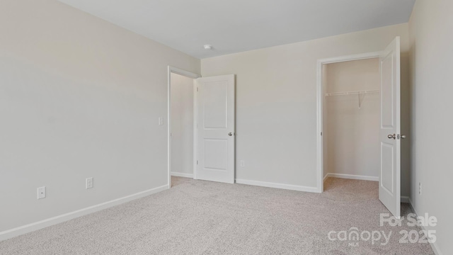 unfurnished bedroom with light carpet, a walk in closet, and a closet