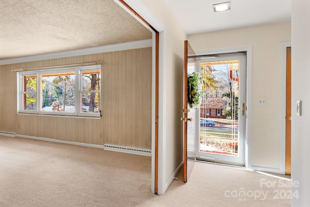 carpeted entryway with wood walls, a baseboard radiator, a textured ceiling, and ornamental molding