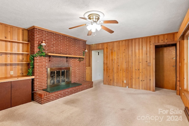 unfurnished living room featuring a textured ceiling, light colored carpet, a brick fireplace, and wood walls