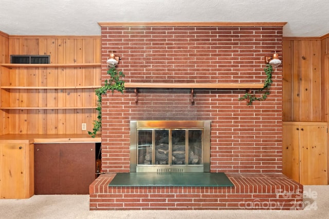 unfurnished living room with wooden walls, carpet flooring, ornamental molding, a fireplace, and a textured ceiling