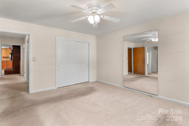 unfurnished bedroom featuring ceiling fan, a closet, and light carpet