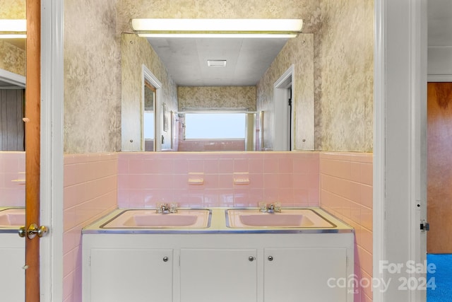 bathroom featuring vanity and tile walls