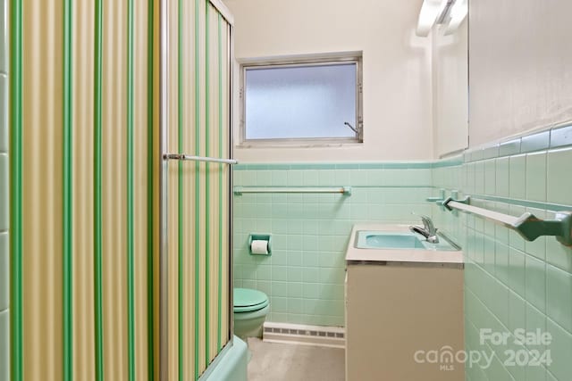 full bathroom with vanity, shower / washtub combination, toilet, baseboard heating, and tile walls