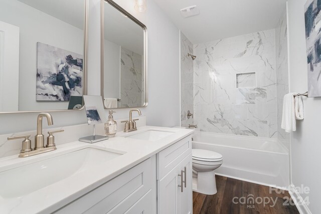 full bathroom featuring hardwood / wood-style floors, tiled shower / bath, toilet, and vanity