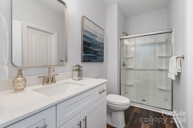 bathroom featuring a shower with door, toilet, hardwood / wood-style floors, and vanity