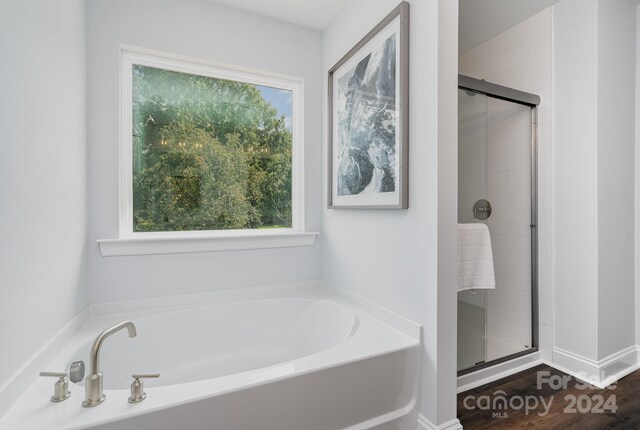 bathroom with a wealth of natural light, shower with separate bathtub, and hardwood / wood-style floors