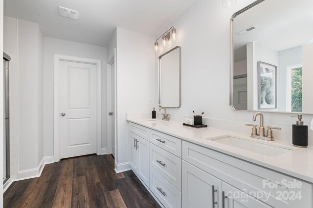 bathroom featuring hardwood / wood-style floors, a shower with door, and vanity