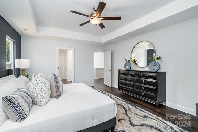 bedroom featuring ceiling fan, a raised ceiling, and dark wood-type flooring