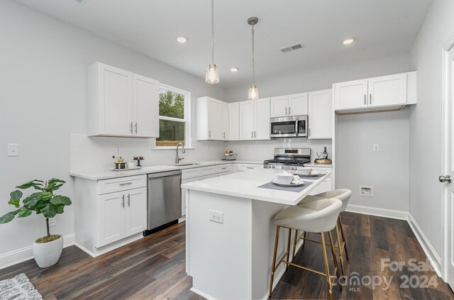 kitchen featuring dark wood-type flooring, a kitchen island, white cabinetry, sink, and stainless steel appliances