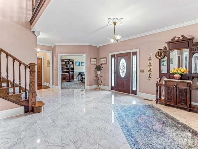 foyer entrance with ornamental molding and an inviting chandelier