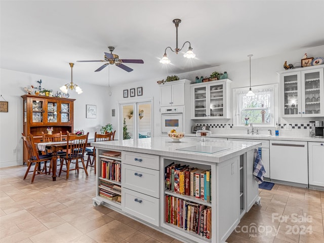 kitchen with white appliances, a kitchen island with sink, hanging light fixtures, tasteful backsplash, and white cabinetry