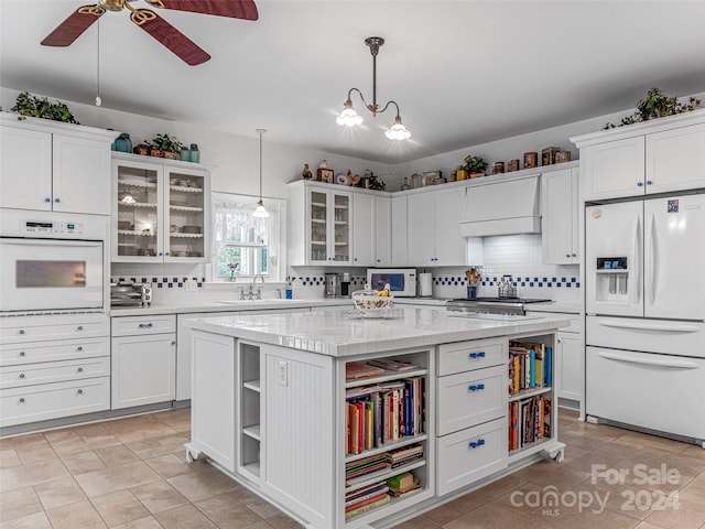 kitchen featuring white cabinets, pendant lighting, white appliances, and a kitchen island