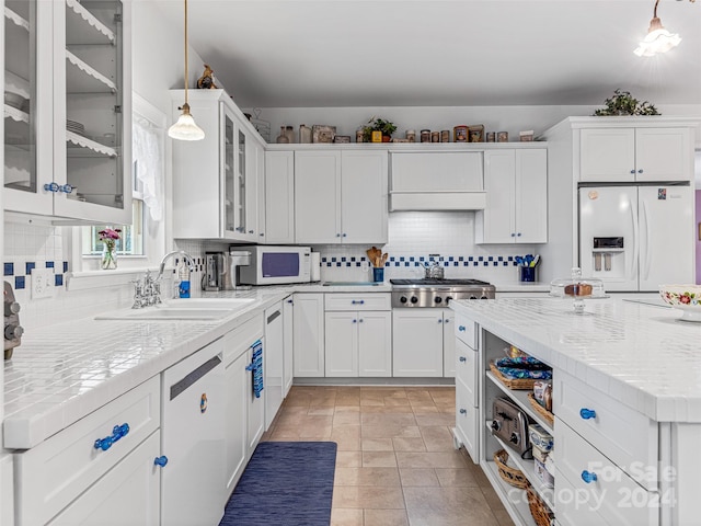 kitchen with pendant lighting, white appliances, sink, decorative backsplash, and white cabinetry