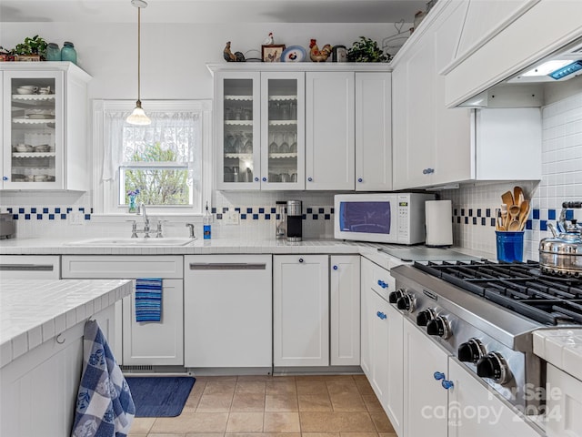 kitchen with premium range hood, white cabinetry, dishwasher, and sink