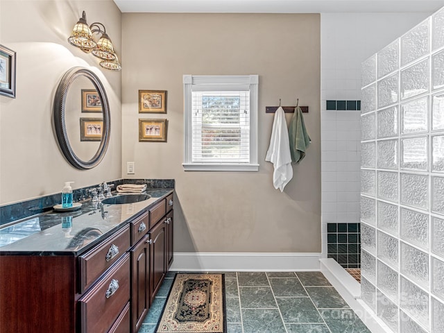 bathroom with a tile shower and vanity