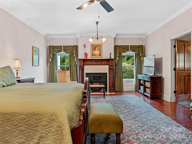 bedroom featuring ceiling fan with notable chandelier, dark hardwood / wood-style floors, ornamental molding, and a tiled fireplace