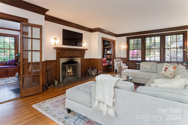 living room featuring hardwood / wood-style floors, wood walls, and crown molding