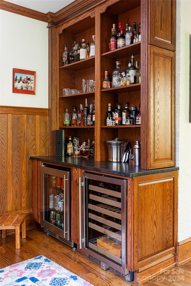 bar featuring wine cooler, crown molding, and hardwood / wood-style flooring