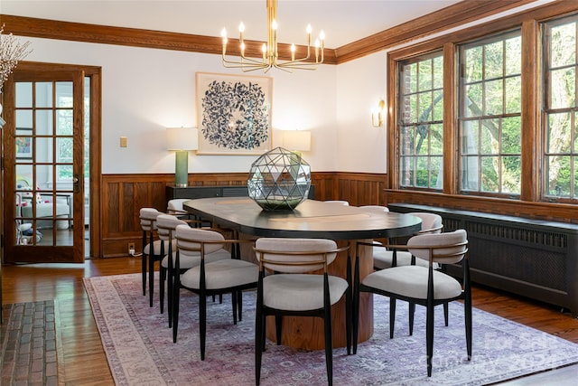 dining area featuring a chandelier, ornamental molding, radiator, and dark wood-type flooring