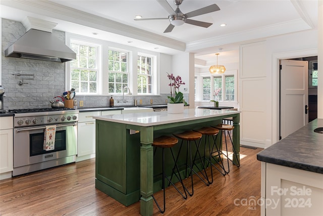 kitchen featuring high end stove, plenty of natural light, a kitchen island, and wall chimney range hood